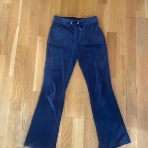 Blå mjukisbyxor från Gina Tricot - Mörkblå mjukisbyxor från Gina Tricot med bootcut-ben och snörning i midjan. Byxorna är gjorda i ett mjukt och skönt material, har två bakfickor och resår i midjan. Perfekta för chill dagar eller när du vill vara extra bekväm.