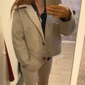 grå kappa från Kappahl  - hej! jag säljer nu min kappa som är perfekt för hösten och våren. Jag har haft jackan i ett år nu och det finns inga besvär med den. Snygg grå jacka från Kappahl i ullmix med stora fickor och bred krage. Jackan har en boxig, lite oversized passform och stängs med knappar framtill. Perfekt för dig som gillar stilrena och trendiga ytterplagg.