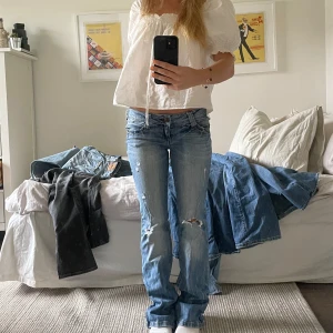Lågmidjade bootcut jeans med slitningar - Säljer ett par ljusblå lågmidjade jeans med bootcut. Superbra skick, bara använda några fåtal gånger. Jag är 160 cm lång 