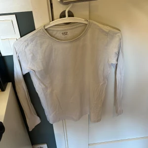 Vit långärmad tröja från 157 - En enkel och clean vit långärmad tröja från 157, perfekt för layering eller att bära som den är. Tröjan har rund hals och är gjord i mjuk bomull som känns skön mot huden. Passformen är normal och den funkar lika bra till jeans som till mjukisbyxor.