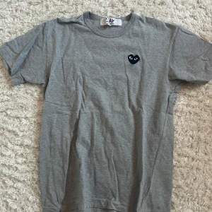 Grå t-shirt Comme des Garçons Play - Säljer min CDG play t-shirt i storlek l (fits M). T-shirten är i extremt bra skick utan några hål eller fläckar. Vid eventuella funderingar/ frågor skriv