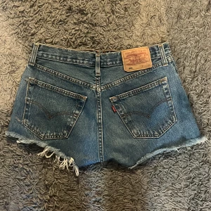 Levi's 501 jeansshorts  - Säljer ett par blå Levi's 501 jeansshorts med hög midja och råa, fransiga kanter. Ena fickan är av vid kanten men går lätt att fixa 