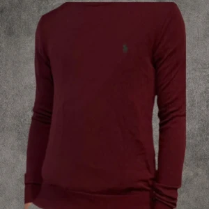 Vinröd merinoullströja Polo Ralph Lauren - Vinröd långärmad tröja från Polo Ralph Lauren i slim fit, tillverkad i mjuk merinoull. Klassisk design med rund hals och broderad logga på bröstet. Perfekt för dig som gillar stilrena och bekväma plagg med premiumkänsla. De har en del defekter, ett litet hål vid midjan och några lagade hål vi handleden. De syns inte vid användning😊