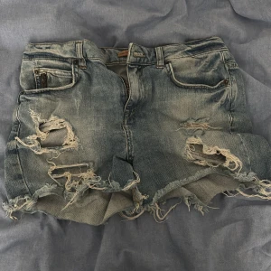 Rippade jeansshorts  - Snygga blå jeansshorts från Perfect Jeans med rejält slitna och rippade detaljer framtill. Klassisk femficksmodell, råa kanter och coolt tvättad denim. Perfekta för en avslappnad och trendig look i sommar.