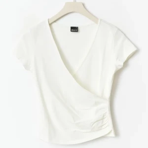 Vit tight wrap top från Gina Tricot, S - Säljer en fräsch vit wrap top från Gina Tricot. Toppen har korta ärmar och v-ringning. Aldrig använt, bara provat. 