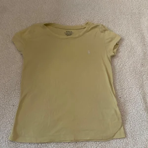 Gul t-shirt från Polo Ralph Lauren 💛 - Snygg gul t-shirt från Polo Ralph Lauren med klassisk broderad logga på bröstet! Tröjan är i ganska stretchigt material och passar mig som är storlek xs! 💗 Fick denna av min kompis för att den inte passade henne men har själv typ aldrig använt den! 🥰