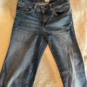 Blå jeansbyxor från 157, XS Short - Snygga blå jeansbyxor från 157 i storlek XS Short. Klassisk femficksmodell med raka ben och coola bakfickor med lock och knapp. Jeansen har en normal passform och är tillverkade i mjukt denimtyg som sitter skönt hela dagen.