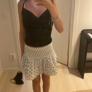 Svart paljettopp från NA-KD - Supersnygg svart croppad topp från NA-KD med paljetter och tunna korsade axelband. Toppen har en v-ringad skärning och sitter tight. Perfekt för dig som vill sticka ut med lite extra glitter och coola detaljer. Säljer pga av nästan ingen användning. Har använt ett par fåtal gånger! Toppen är från NA-KD i storlek xxs! Det är inga defekter! Skriv om ni undrar något eller om ni vill ha flera bilder!💗