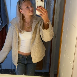 Teddyjacka H&M - Mysig beige teddyjacka med dragkedja framtill och två stora fickor. Säljer pga att jag har dubbletter, denna jackan är perfekt nu till hösten!! Jackan har en avslappnad passform och hög krage, perfekt för lager-på-lager. Materialet är fluffigt och ger en chill vibe till din outfit. Nypris ca 500kr. 