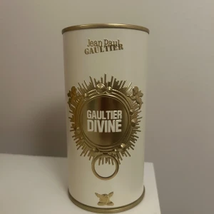 Jean Paul Gaultier Divine parfym - Unik parfymflaska från Jean Paul Gaultier Divine i guldigt glas, formad som en kvinnokropp med ikonisk konformad byst och detaljer i guld. Kommer med exklusiv vit och guldig förpackning som ger lyxig känsla. Perfekt för dig som vill sticka ut med din doft.