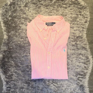 Ralph Lauren Skjorta Rosa Randig - Klassisk rosa- och vitrandig skjorta från Ralph Lauren i tidlös design. Perfekt för både vardag och mer uppklädda tillfällen.