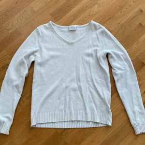 Vit v-ringad stickad tröja från Vila - Säljer en enkel och stilren vit stickad tröja från Vila i storlek S. Tröjan har v-ringad hals, långa ärmar och ribbade muddar vid ärmslut och nederkant. Du står för frakten, vid mer info skriv 