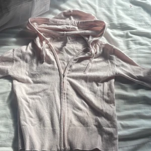 Ljusrosa hoodie från Gina Tricot - Säljer en ljusrosa hoodie från Gina Tricot med dragkedja framtill och snörning i huvan. Tröjan har långa ärmar och ribbade muddar vid ärmslut och nederkant. Mjuk och skön bomullskänsla, perfekt för chill dagar. Passar dig som gillar enkel och clean stil.