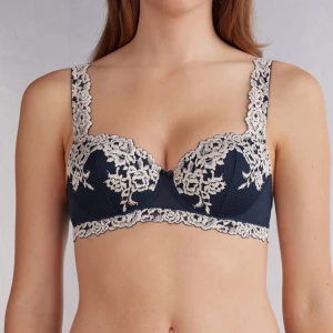 Mörkblå intimissimi bh - Supersnygg mörkblå bh med ljus spets och blommigt broderi längs kanterna och axelbanden. Figurnära passform och v-ringad skärning framtill. Nypris 520:-