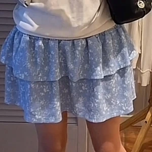 Blå volangkjol med blommigt mönster - Supersöt blå kjol med vita små blommor och dubbla volanger. Skriv om fler bilder!💕💕