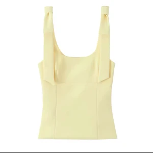 Gul linnetopp med knytband - Snygg ljusgul linnetopp med breda axelband som knyts upptill. Toppen har en fyrkantig ringning och figurnära passform, perfekt för varma dagar. Slutsåld från Zara och helt ny!