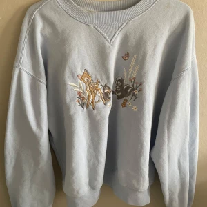 Ljusblå sweatshirt med Bambi-brodyr - Superfin ljusblå sweatshirt med broderat Bambi-motiv framtill. Tröjan har rund halsringning och långa ärmar. Perfekt för dig som gillar Disney och vill ha en söt och bekväm tröja.
