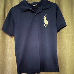 Mörkblå pikétröja från Polo Ralph Lauren - Säljer en klassisk mörkblå pikétröja från Polo Ralph Lauren med  broderad logga på bröstet | Använd några ett fåtal gånger, inga defekter | Stolek M | 