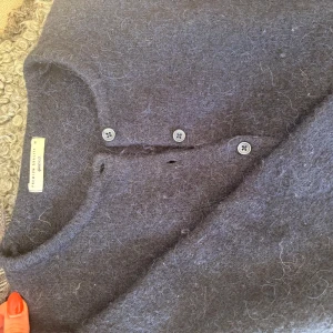 Mörkgrå kofta från Gina Tricot - Mysig mörkgrå kofta från Gina Tricot med knappar framtill. Koftan är stickad och har en klassisk rund halsringning. Perfekt för lager-på-lager och enkel att matcha med olika outfits.