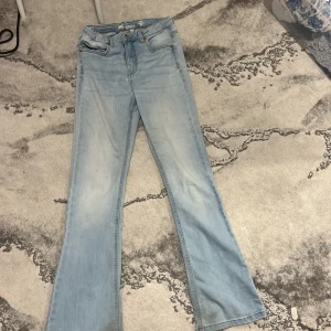 Ljusblå bootcut jeans från LAB Industries - Ljusblå jeans med bootcut passform från LAB Industries. Klassisk femficksmodell med knapp och dragkedja i gylfen. Jeansen har en lätt tvättad look och är tillverkade i denim.