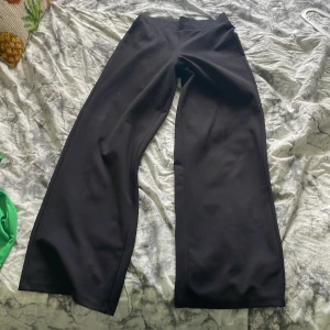 Svarta vida byxor - Säljer ett par svarta byxor med vid passform och hög midja. Byxorna har en stilren look och är perfekta för dig som gillar en avslappnad men trendig stil.