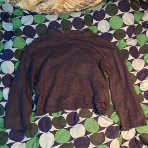 Mörkbrun stickad croppad tröja från 157 - Mysig mörkbrun stickad tröja från 157 i croppad modell. Tröjan har långa ärmar och en enkel, klassisk design som passar perfekt till höst och vinter. Ribbstickade muddar vid ärmslut och nederkant.