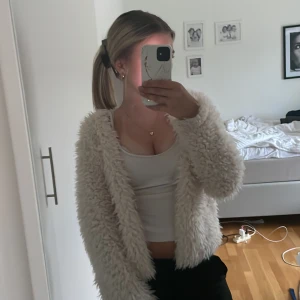 Vit fluffig kofta från Gina Tricot - Säljer en supermjuk och fluffig vit kofta från Gina Tricot. Koftan har lång ärm och är tillverkad i ett pälsliknande material som är mysigt och mjukt. Perfekt att ha på sig när det är kallt ute.