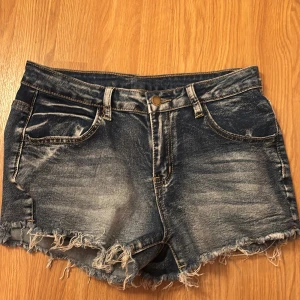 Mörkblå jeansshorts med fransar -  Jag köpte dom på vinted men var för små för mig. Snygga mörkblå jeansshorts med slitna detaljer och fransig kant nertill. Klassisk femficksmodell med broderade bakfickor och knappgylf. Perfekta för sommaren och ger en cool, avslappnad look.