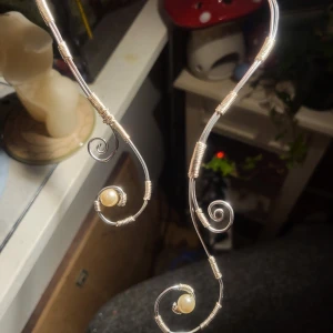 Handgjord halsband i silverfärgad metall med pärlor - Unik halsband i silverfärgad metall med spiralformad design och infattade vita pärlor. Perfekta för dig som vill sticka ut med ett elegant och konstnärligt smycke.