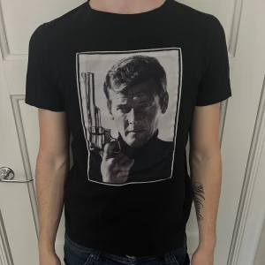 Svart t-shirt med Roger Moore-motiv från Limitato - Cool svart t-shirt från Limitato med stort tryck av Roger Moore. 