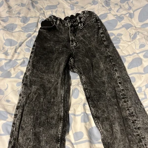 Svarta loose fit jeans från H&M - Säljer ett par svarta loose fit jeans från H&M med justerbar midja och raka ben. Jeansen har en tvättad look och stora bakfickor. Perfekta för dig som gillar en avslappnad stil.