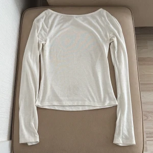 Vit långärmad topp - Säljer en enkel och stilren vit långärmad topp med rund halsringning. Perfekt att matcha med jeans eller kjol för en clean look. Tunn och mjuk i materialet.