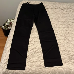 Svarta jeans byxor  med resårmidja - Svarta mjukisbyxor med rak passform och resår i midjan. Perfekta för en avslappnad stil och bekväma dagar. Byxorna har en enkel design utan synliga detaljer och är tillverkade i ett mjukt material.