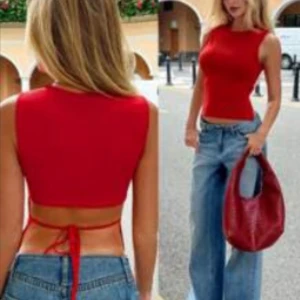 Röd croppad topp med knyt öppen rygg - Trendig röd backless öppen rygg croppad linnetopp med knyt i ryggen. Toppen är ärmlös och har en tight passform, perfekt till jeans eller kjol. Enkel och stilren design som sticker ut med sitt knytband bak. Aldrig använd så jag råkade beställa 2 styckna