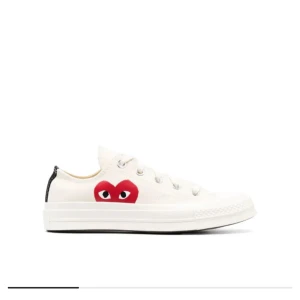 Converse x Comme des Garçons Play vita sneakers - Säljer ett par vita Converse x Comme des Garçons Play sneakers med det ikoniska röda hjärtat på sidan. Skorna har snörning, platt sula och är tillverkade i canvas. Perfekta för dig som gillar stilrena och trendiga sneakers. Skorna är inte andvända! 
