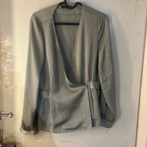 Blus  - En grön blus med knappar på sidan, funkar alltså som både blus men även ”kofta”. Den är i ett skönt luftigt material och i en fin grön färg perfekt nu till sommar!