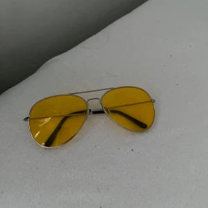 Gula pilotbågar med metallram - Snygga pilotglasögon med tunna silverfärgade metallbågar och gula glas. Klassisk aviator-modell som ger en cool retrostil. Passar perfekt för dig som vill sticka ut med färgade linser.