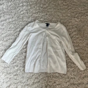 Vit kofta från H&M BASIC - En klassisk vit kofta från H&M BASIC med rund halsringning och knappar framtill. Tröjan har långa ärmar och ribbade muddar vid ärmslut och nederkant. Perfekt att slänga över en topp eller klänning.