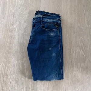 Replay Anbass - Säljer ett par mörkblå jeans från Replay. Jeansen har diskreta slitningar och slim passform, samt läderpatch med logga bak i midjan.