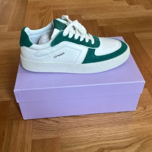 Vita och gröna sneakers från Copenhagen Studios - Säljer ett par helt oanvända vita och gröna sneakers från Copenhagen Studios, modell CPH264. Skorna har snygga gröna detaljer i mocka och vit skinnbas, samt klassisk snörning och perforerad tå. 