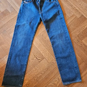 Blå jeans från Diesel Industry - Klassiska blå jeans från Diesel Industry med raka ben och femficksmodell. Jeansen har normal passform och är tillverkade i slitstarkt denimtyg. Perfekta för dig som gillar en tidlös och enkel stil.