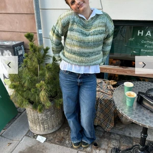 Grönmelerad stickad tröja från designbysi - Mysig stickad tröja i gröna och vita nyanser med v-ringad hals. Tröjan har lång ärm och en avslappnad passform. Köpt på designbysi och använd 1 gång. Nypris 500, one size