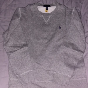 Grå sweatshirt från Polo Ralph Lauren -  grå sweatshirt från Polo Ralph Lauren med rund halsringning och broderad logga på bröstet. Tröjan har långa ärmar och ribbade muddar vid ärmslut och nederkant. Men pris går alltid att diskutera 