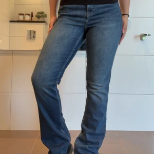 Blå bootcut jeansbyxor  - Säljer ett par klassiska blå jeansbyxor från Kappahl i storlek 38. Byxorna har bootcut-passform och normal midja, med snygga sömmdetaljer och femficksdesign. Perfekta till en avslappnad stil.