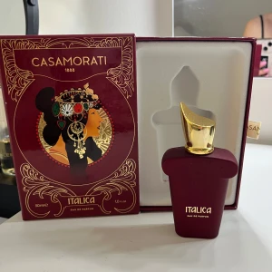 Casamorati Italica Eau de Parfum - Lyxig parfym från Casamorati i serien Italica. Flaskan är vinröd med guldfärgat lock och rymmer 30 ml/ ca 25ml kvar, Parfymen är tillverkad i Italien och innehåller bland annat mandel, vanilj och mjölkiga noter. Perfekt för en gourmand älskare 