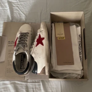 Golden Goose sneakers med röd stjärna - Säljer nu dessa riktigt sköna Golden Goose skorna i en ovanlig färg (nypris ca 6000kr). Skorna har synliga hål vid hälen men det är inget en som skomakare inte kan fixa.                                 Original box medföljer samt dustbags och GGDB passport, självklart äkta.                                        Hör gärna av her vid övriga frågor ;).                           Priset är ej satt i sten!