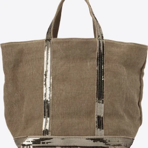 Beige shoppingväska med paljettdetaljer - Stor beige shoppingväska från Vanessa Bruno med glittriga silverpaljetter på handtag och botten. Väskan är tillverkad i linnematerial och har ett stort huvudfack med dragkedja på insidan. Perfekt för att bära med sig allt man behöver.