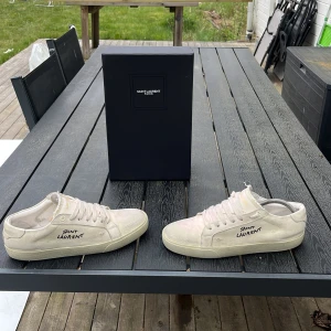 Saint Laurent vita sneakers - Säljer ett par vita Saint laurant dom är nya har använt 3 gånger endast med sko kartong och dust bag och alla tillbehör storlek 41 men funkar för 42 med