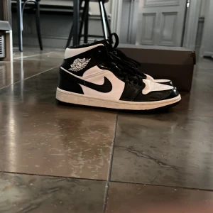 Nike Air Jordans svartvita sneakers - Säljer ett par klassiska Nike Air Jordans i svart och vitt. Skorna har hög modell, snörning och den ikoniska swoosh-loggan på sidan. Använda men ändå ganska bra skick. Box ingår.