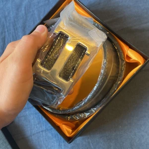 Svart skärp Personal Tailor skinn - Stilrent svart bälte från Personal Tailor i äkta skinn med snyggt silverfärgat spänne. Bältet har en klassisk design och levereras i en exklusiv presentask. Perfekt accessoar för att lyfta din outfit.